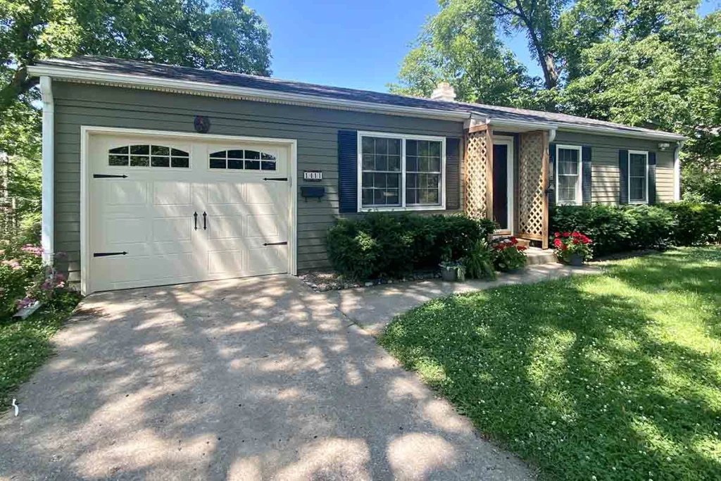 Single-story home exterior with matching gray siding, white trim and a continuous roofline linking the garage and living space, a Pinnacle Projects remodel in Mid-Missouri.