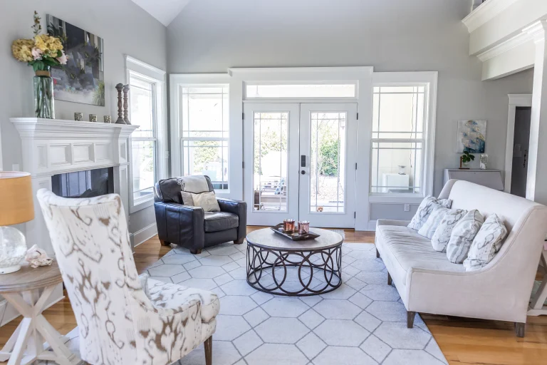 Bright living room with a white sofa, patterned chair, dark armchair, round coffee table, fireplace and glass doors