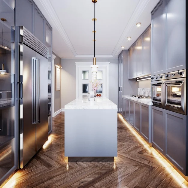 Narrow gray kitchen with a white island, stainless steel fridge, two wall ovens, pendant lights and herringbone floor